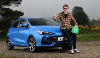 Auto Express content editor Ryan Birch sitting on the MG3's bonnet while holding a pound note and a gerry can